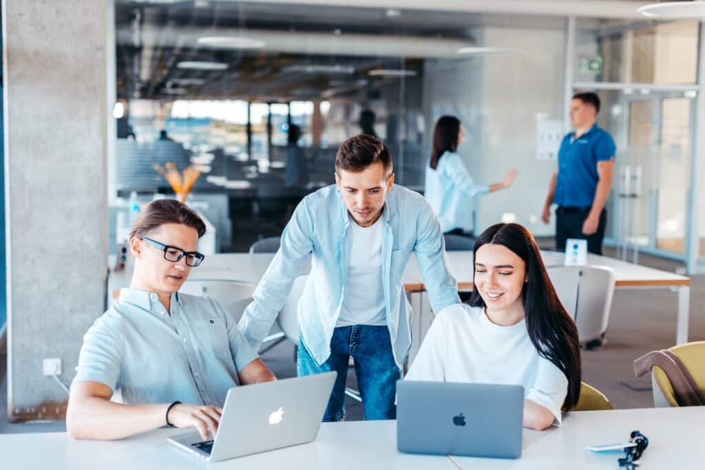 a group of people sitting around a table with laptops